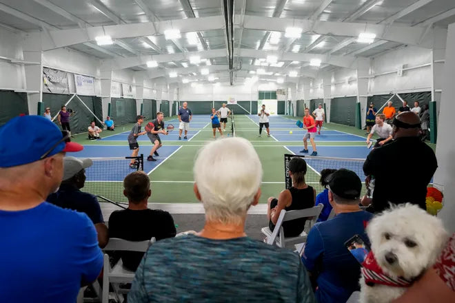 people seated at pickle shack watching a pickleball event with players